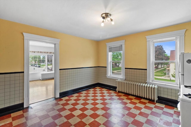 3700 E Hammond Ave, Cudahy, WI 53110 - spare room featuring radiator heating unit, plenty of natural light, a wainscoted wall, tile walls, and tile patterned floors
