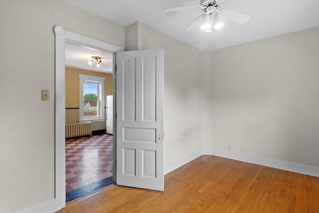 3700 E Hammond Ave, Cudahy, WI 53110 - unfurnished room featuring radiator heating unit, ceiling fan, baseboards, light wood-type flooring, and lofted ceiling
