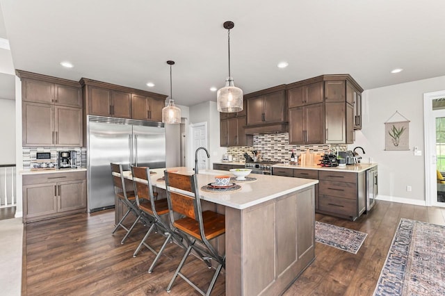 N56W27213 Crispin Ct, Lisbon, WI 53089 - kitchen featuring premium appliances, tasteful backsplash, light countertops, dark wood finished floors, and dark brown cabinetry