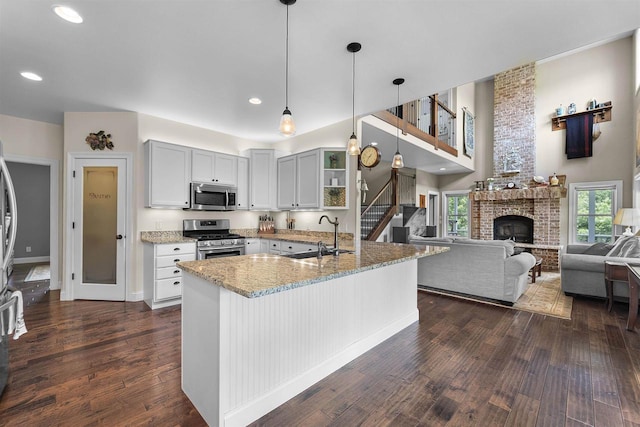 5119 Reynolds Ave, Waunakee, WI 53597 - kitchen with stainless steel appliances, a sink, light stone countertops, dark wood-style floors, and a brick fireplace