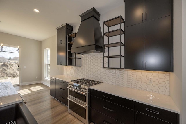 624 Green Bay Rd, Thiensville, WI 53092 - kitchen featuring range with two ovens, custom exhaust hood, light wood-type flooring, dark cabinetry, and recessed lighting