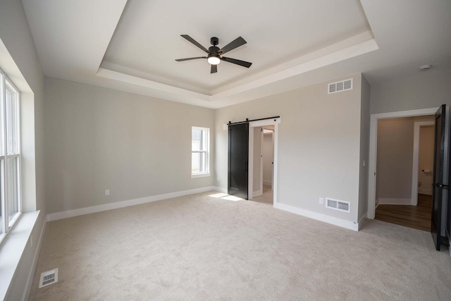 624 Green Bay Rd, Thiensville, WI 53092 - unfurnished bedroom with a tray ceiling, light colored carpet, baseboards, and a barn door