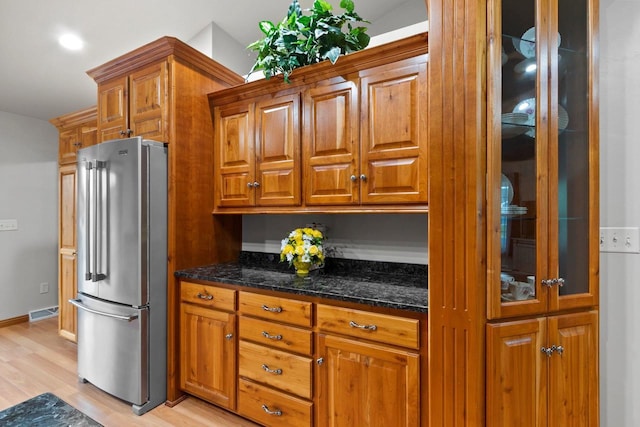 1603 Pine Tree Ln, Luxemburg, WI 54217 - kitchen featuring freestanding refrigerator, brown cabinetry, light wood-type flooring, and dark stone countertops
