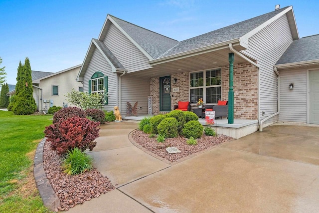 1603 Pine Tree Ln, Luxemburg, WI 54217 - view of front of property featuring a porch, roof with shingles, brick siding, and a front lawn