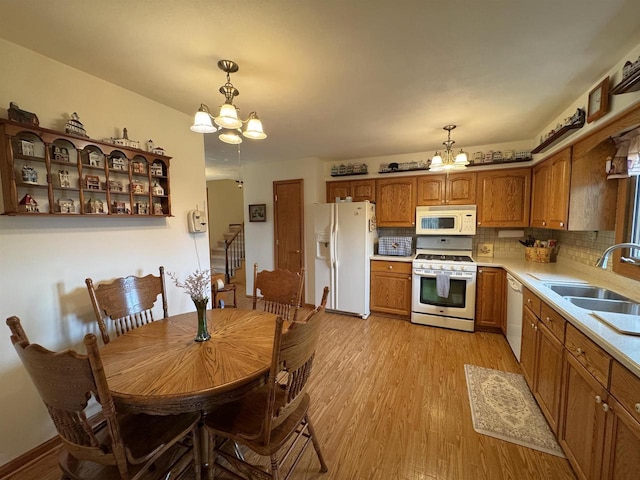 137 24th Ave, Monroe, WI 53566 - kitchen with white appliances, a chandelier, a sink, and brown cabinets