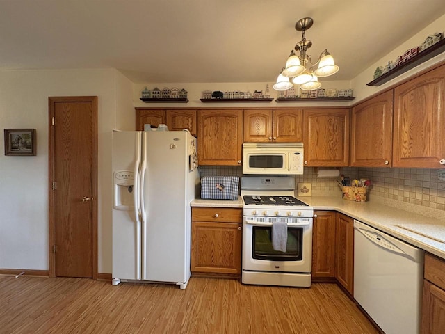 137 24th Ave, Monroe, WI 53566 - kitchen featuring white appliances, brown cabinets, light wood-style flooring, a chandelier, and light countertops