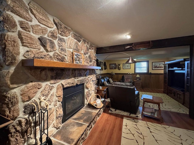 137 24th Ave, Monroe, WI 53566 - living area featuring wood finished floors, wainscoting, a textured ceiling, arched walkways, and a stone fireplace