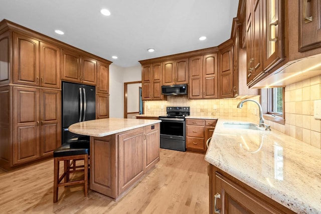 209 E Timberline Dr, Appleton, WI 54913 - kitchen with stainless steel appliances, a sink, light wood finished floors, a kitchen island, and light stone counters