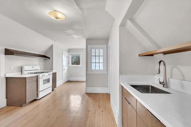 2505 N Oakland Ave Unit 2507, Milwaukee, WI 53211 - kitchen with gas range gas stove, open shelves, a sink, light countertops, and vaulted ceiling