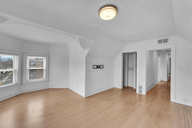 2505 N Oakland Ave Unit 2507, Milwaukee, WI 53211 - unfurnished living room featuring vaulted ceiling, light wood finished floors, and baseboards