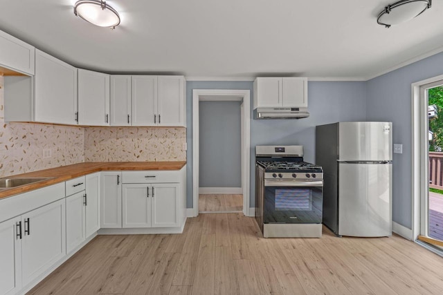 603 Spring St, Lake Geneva, WI 53147 - kitchen with appliances with stainless steel finishes, under cabinet range hood, butcher block counters, light wood finished floors, and white cabinetry