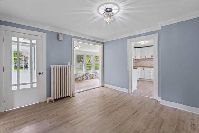 603 Spring St, Lake Geneva, WI 53147 - empty room with radiator, ornamental molding, light wood-style flooring, a chandelier, and baseboards