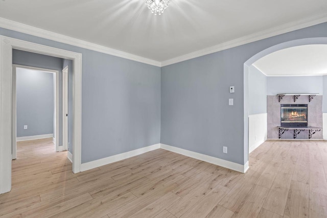 603 Spring St, Lake Geneva, WI 53147 - spare room with arched walkways, light wood finished floors, a tiled fireplace, baseboards, and crown molding