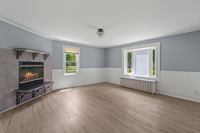 603 Spring St, Lake Geneva, WI 53147 - unfurnished living room with radiator heating unit, a wainscoted wall, a glass covered fireplace, and wood finished floors