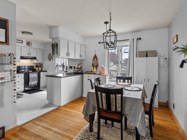 1801 S 24th St, Manitowoc, WI 54220 - dining area featuring a chandelier, light wood-style flooring, and baseboards