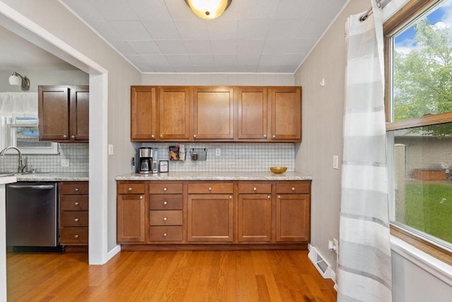 2602 26th St, South Street, La Crosse, WI 54601 - kitchen with dishwasher, brown cabinets, light wood-type flooring, decorative backsplash, and plenty of natural light