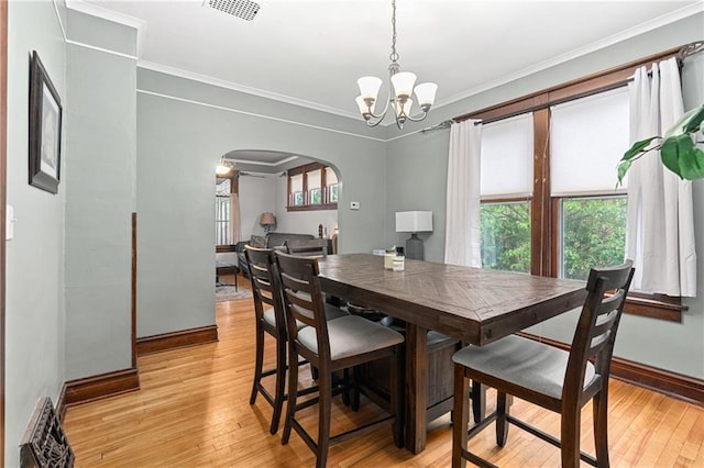 1528 Bellevue Ave, Eau Claire, WI 54703 - dining space featuring arched walkways, a chandelier, baseboards, light wood finished floors, and crown molding