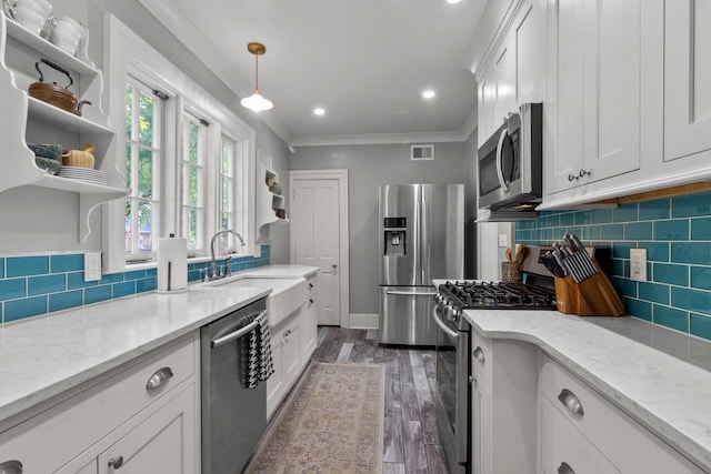 234 Warren St, Lake Geneva, WI 53147 - kitchen featuring appliances with stainless steel finishes, a sink, white cabinetry, tasteful backsplash, and ornamental molding