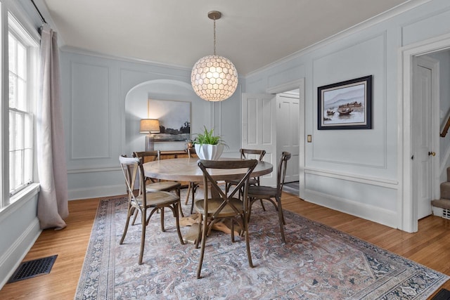 234 Warren St, Lake Geneva, WI 53147 - dining space featuring a decorative wall, healthy amount of natural light, light wood finished floors, crown molding, and arched walkways