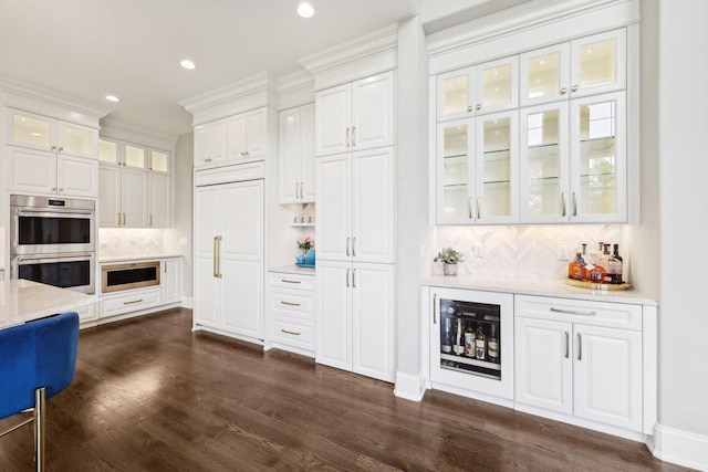 10031 N Range Line Rd, Mequon, WI 53092 - indoor dry bar with stainless steel double oven, dark wood-type flooring, tasteful backsplash, recessed lighting, and crown molding