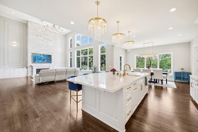 10031 N Range Line Rd, Mequon, WI 53092 - kitchen with a chandelier, a large fireplace, dark wood-style flooring, white cabinets, and recessed lighting