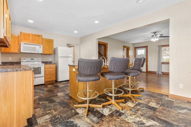 N3438 State Rd 76, Hortonville, WI 54944 - kitchen with white appliances, a kitchen bar, a ceiling fan, recessed lighting, and baseboards