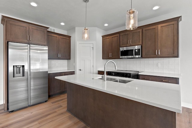 1925 Creekwood Ct, Manitowoc, WI 54220 - kitchen with appliances with stainless steel finishes, a sink, dark brown cabinetry, an island with sink, and light wood-style floors