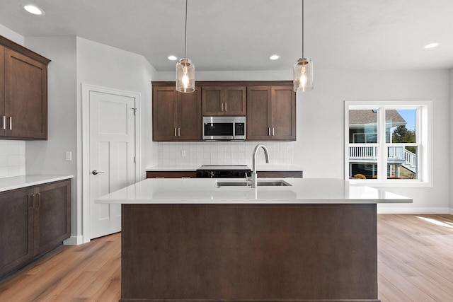 1925 Creekwood Ct, Manitowoc, WI 54220 - kitchen featuring stainless steel microwave, a sink, light wood-type flooring, decorative backsplash, and recessed lighting