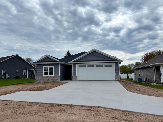 1925 Creekwood Ct, Manitowoc, WI 54220 - ranch-style home with stone siding, concrete driveway, an attached garage, and central AC unit