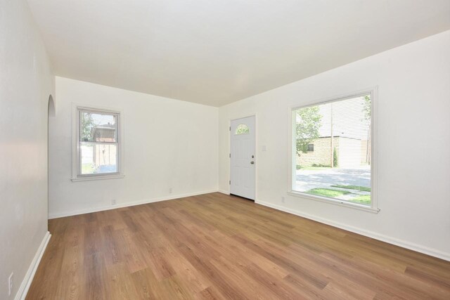 4757 N 21st St, Milwaukee, WI 53209 - empty room with light wood-type flooring, healthy amount of natural light, arched walkways, and baseboards