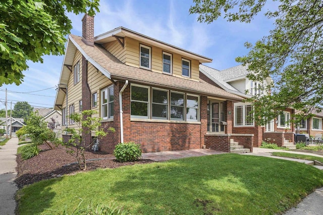 2002 Yahara Pl, Madison, WI 53704 - view of front facade with a chimney, brick siding, a front yard, and roof with shingles