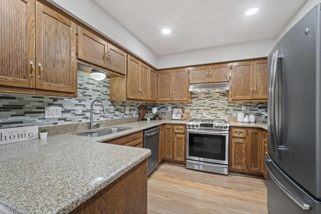 920 Oakwood Ln Unit C, Brookfield, WI 53045 - kitchen with stainless steel appliances, under cabinet range hood, brown cabinets, backsplash, and light wood finished floors
