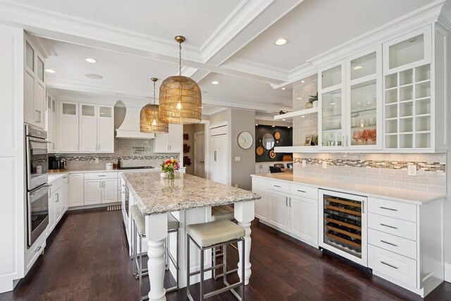 5570 Surrey Ln, Waunakee, WI 53597 - kitchen with wine cooler, a center island, decorative backsplash, wall chimney exhaust hood, and ornamental molding