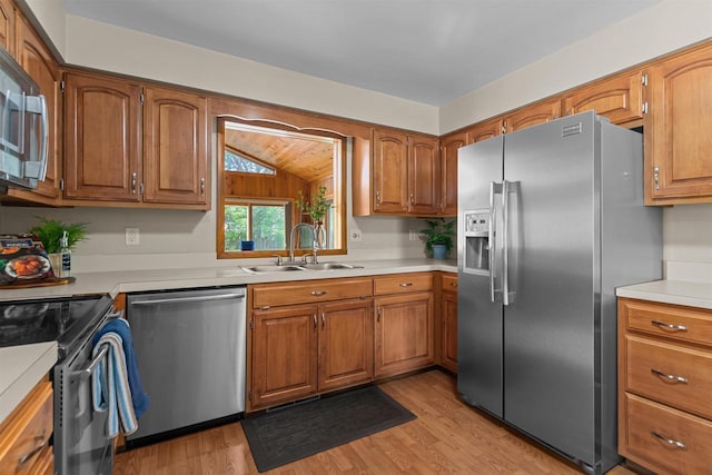 1001 S Matthias St, Appleton, WI 54915 - kitchen with stainless steel appliances, a sink, light wood-style flooring, vaulted ceiling, and brown cabinetry