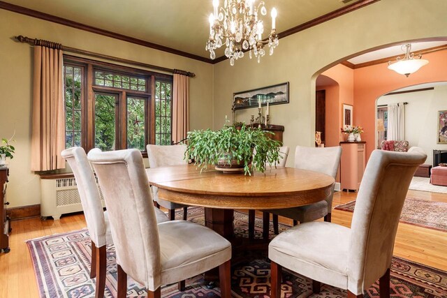 1705 Emerson St, Beloit, WI 53511 - dining area with light wood-style flooring, ornamental molding, arched walkways, radiator, and baseboards