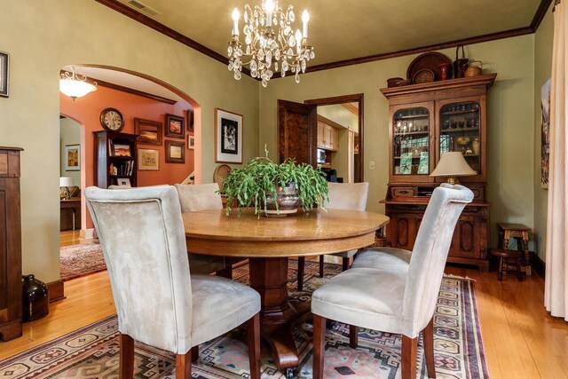 1705 Emerson St, Beloit, WI 53511 - dining area featuring arched walkways, light wood-style floors, crown molding, and a chandelier