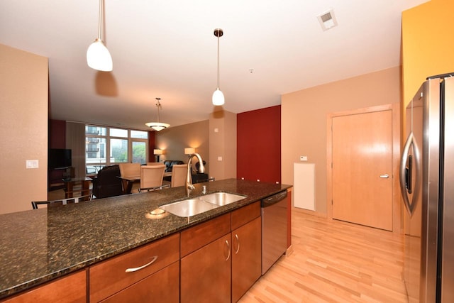 601 E Ogden Ave Unit 411, Milwaukee, WI 53202 - kitchen featuring appliances with stainless steel finishes, a sink, light wood finished floors, brown cabinets, and pendant lighting