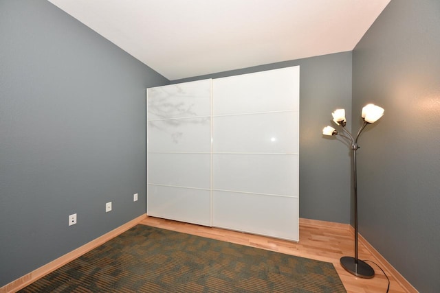601 E Ogden Ave Unit 411, Milwaukee, WI 53202 - unfurnished bedroom with wood finished floors, baseboards, and vaulted ceiling