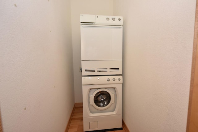 601 E Ogden Ave Unit 411, Milwaukee, WI 53202 - washroom featuring stacked washer / dryer, wood finished floors, and baseboards