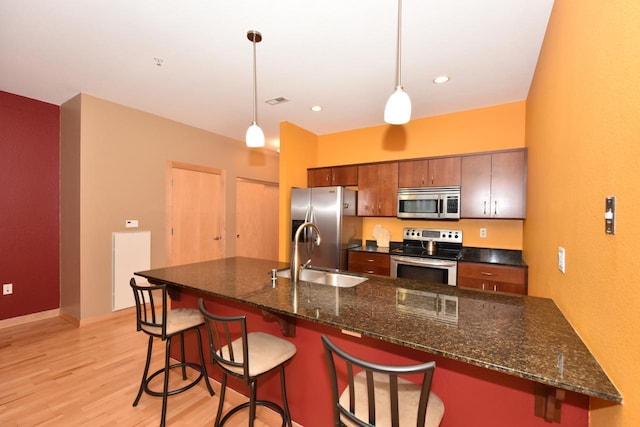 601 E Ogden Ave Unit 411, Milwaukee, WI 53202 - kitchen with stainless steel appliances, a sink, light wood finished floors, a kitchen bar, and pendant lighting