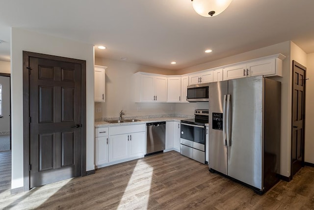 910-920 Green Pastures Trl, Plover, WI 54467 - kitchen with appliances with stainless steel finishes, a sink, white cabinets, light countertops, and dark wood-style flooring