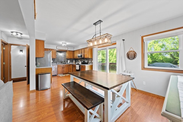 1529 Vogt Dr, West Bend, WI 53095 - dining room featuring plenty of natural light, light wood-style flooring, and baseboards
