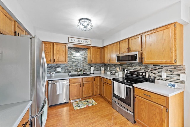 1529 Vogt Dr, West Bend, WI 53095 - kitchen featuring stainless steel appliances, a sink, tasteful backsplash, and light wood finished floors