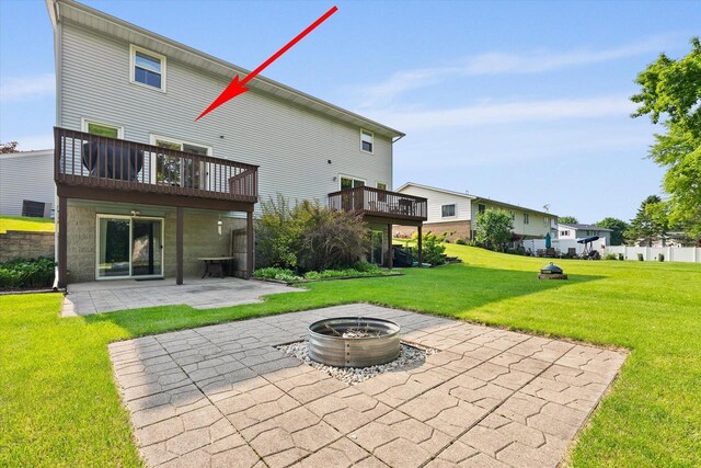 1529 Vogt Dr, West Bend, WI 53095 - back of property featuring a patio area, a fire pit, a lawn, and a wooden deck