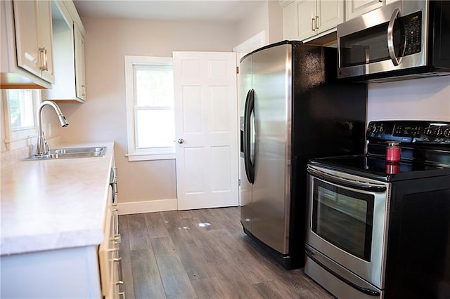 121 Pear St, Chippewa Falls, WI 54729 - kitchen with stainless steel appliances, a sink, dark wood-type flooring, light countertops, and baseboards