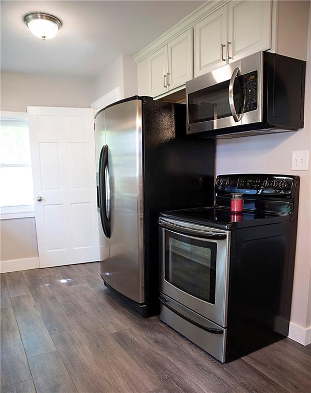 121 Pear St, Chippewa Falls, WI 54729 - kitchen featuring appliances with stainless steel finishes, dark wood-style floors, baseboards, and white cabinetry