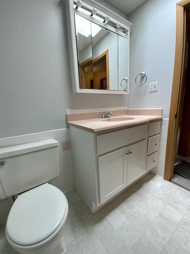 874 E Petunia Ln, Beloit, WI 53511 - half bath featuring vanity, tile walls, and a wainscoted wall