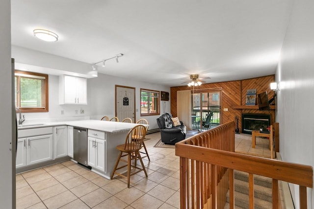 1251 Canyon Rd Unit 40, Wisconsin Dells, WI 53965 - kitchen featuring open floor plan, stainless steel dishwasher, a peninsula, wooden walls, and white cabinetry