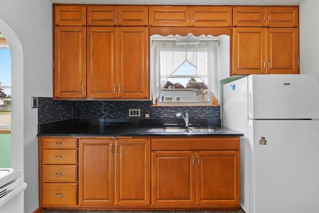 1013 28th St, Two Rivers, WI 54241 - kitchen featuring freestanding refrigerator, arched walkways, a sink, backsplash, and brown cabinets
