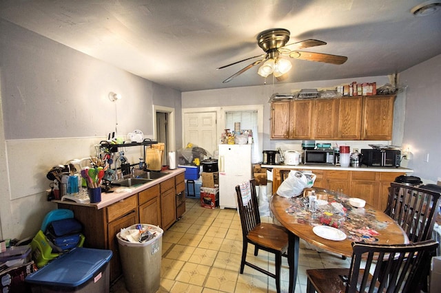 1033 S 11th St, Manitowoc, WI 54220 - kitchen with stainless steel microwave, freestanding refrigerator, ceiling fan, light countertops, and brown cabinetry